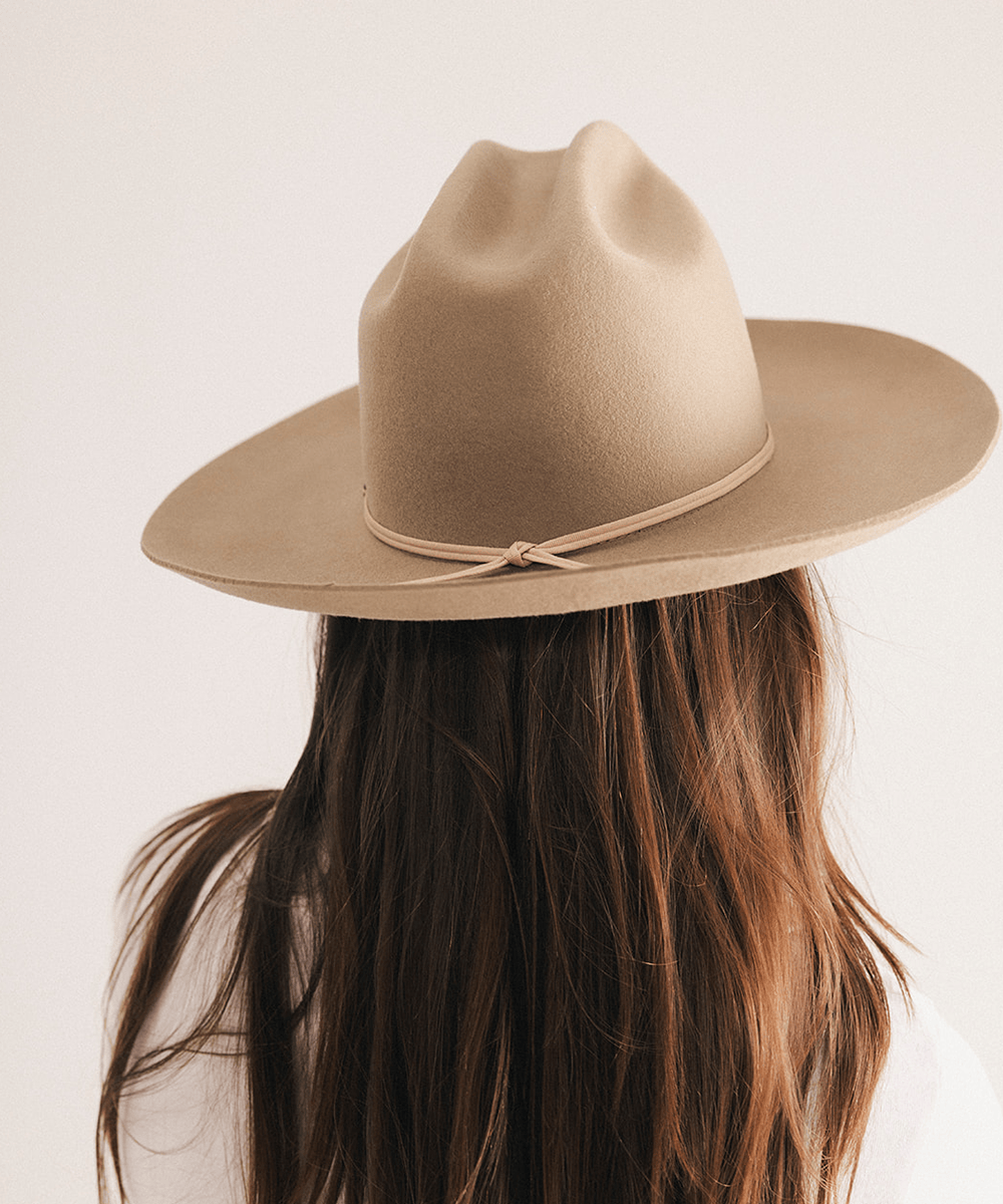 Woman wearing a western felt hat on a white background #color_tan