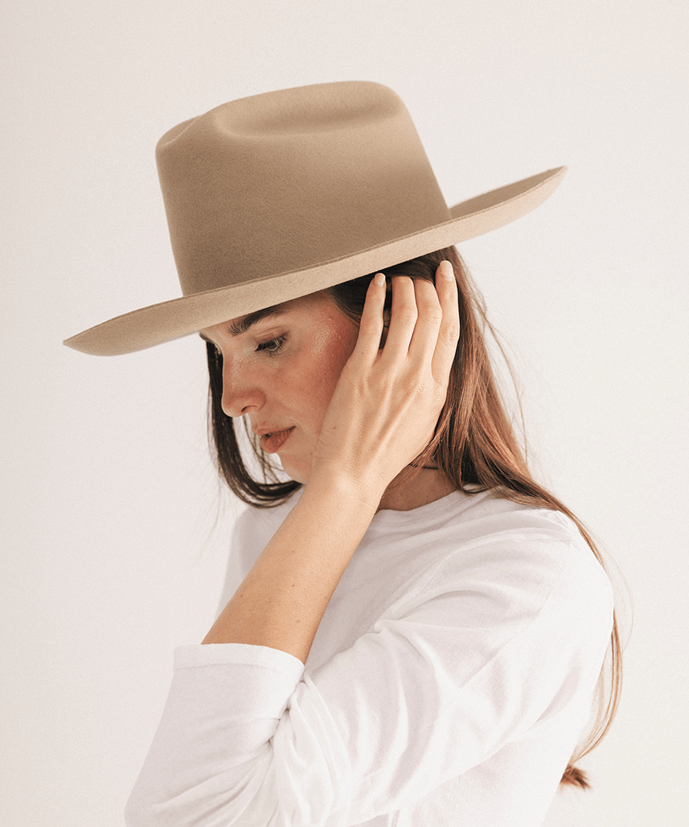 Woman wearing a western felt hat on a white background #color_tan