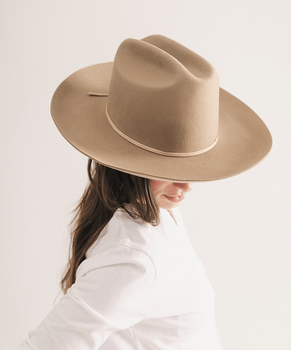 Woman wearing a western felt hat on a white background #color_tan