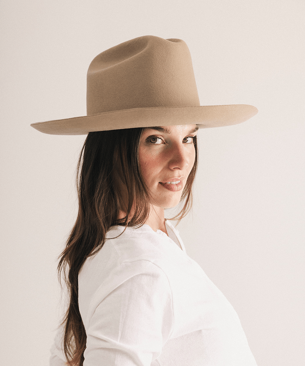 Woman wearing a western felt hat on a white background #color_tan