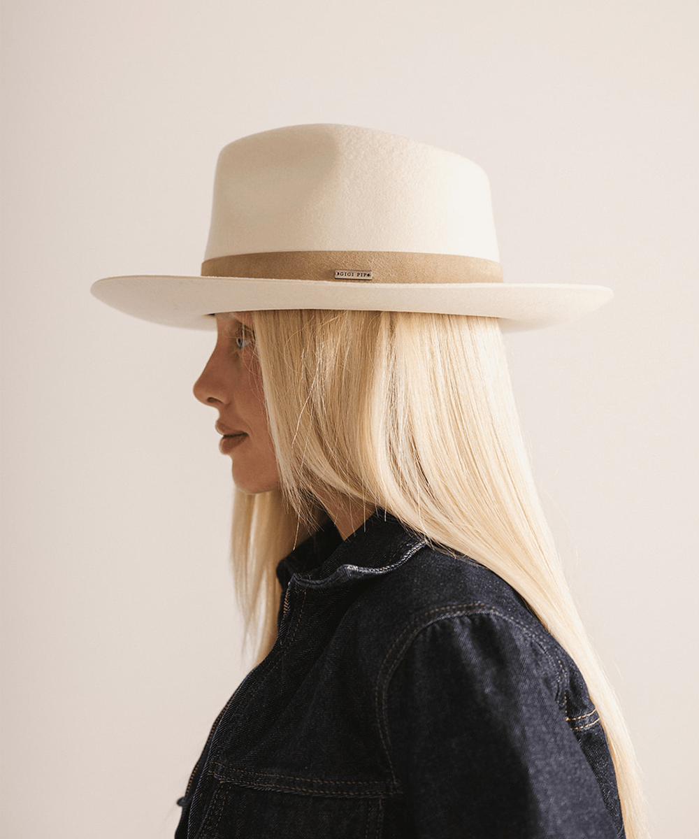 Woman with long hair wearing an off white felt fedora hat with a band against a plain background  #color_off white