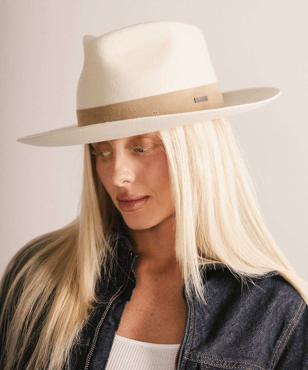 Woman with long hair wearing an off white felt fedora hat with a band against a plain background  #color_off white