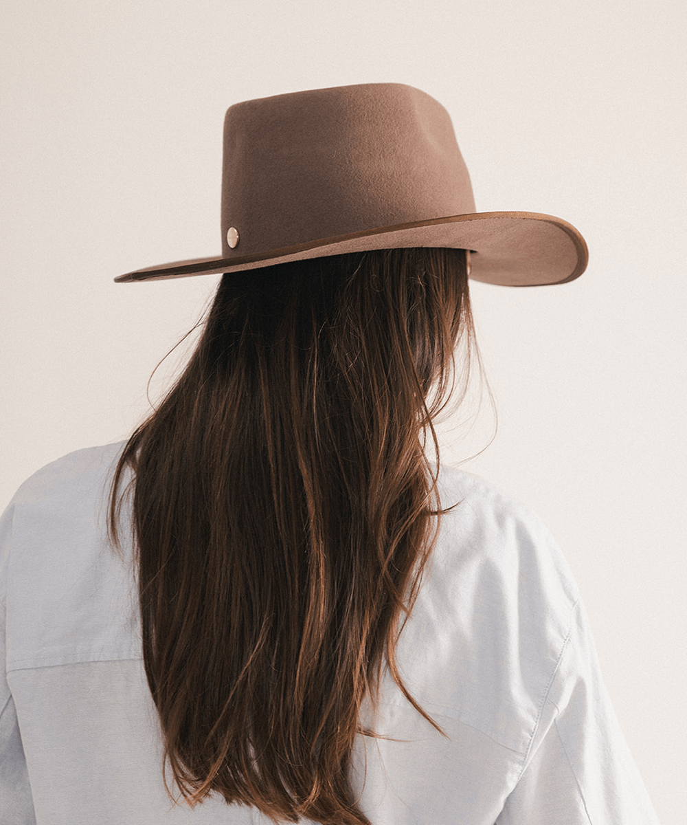 Woman wearing a brown felt hat on a white background #color_brown