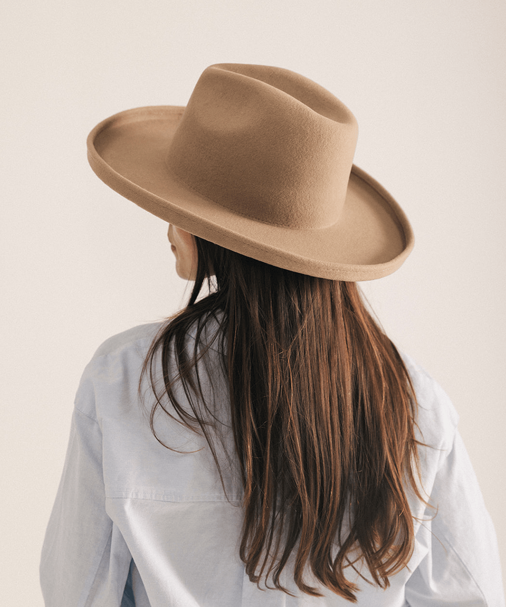 Woman wearing a tan pencil brim felt fedora hat on a white background #color_tan