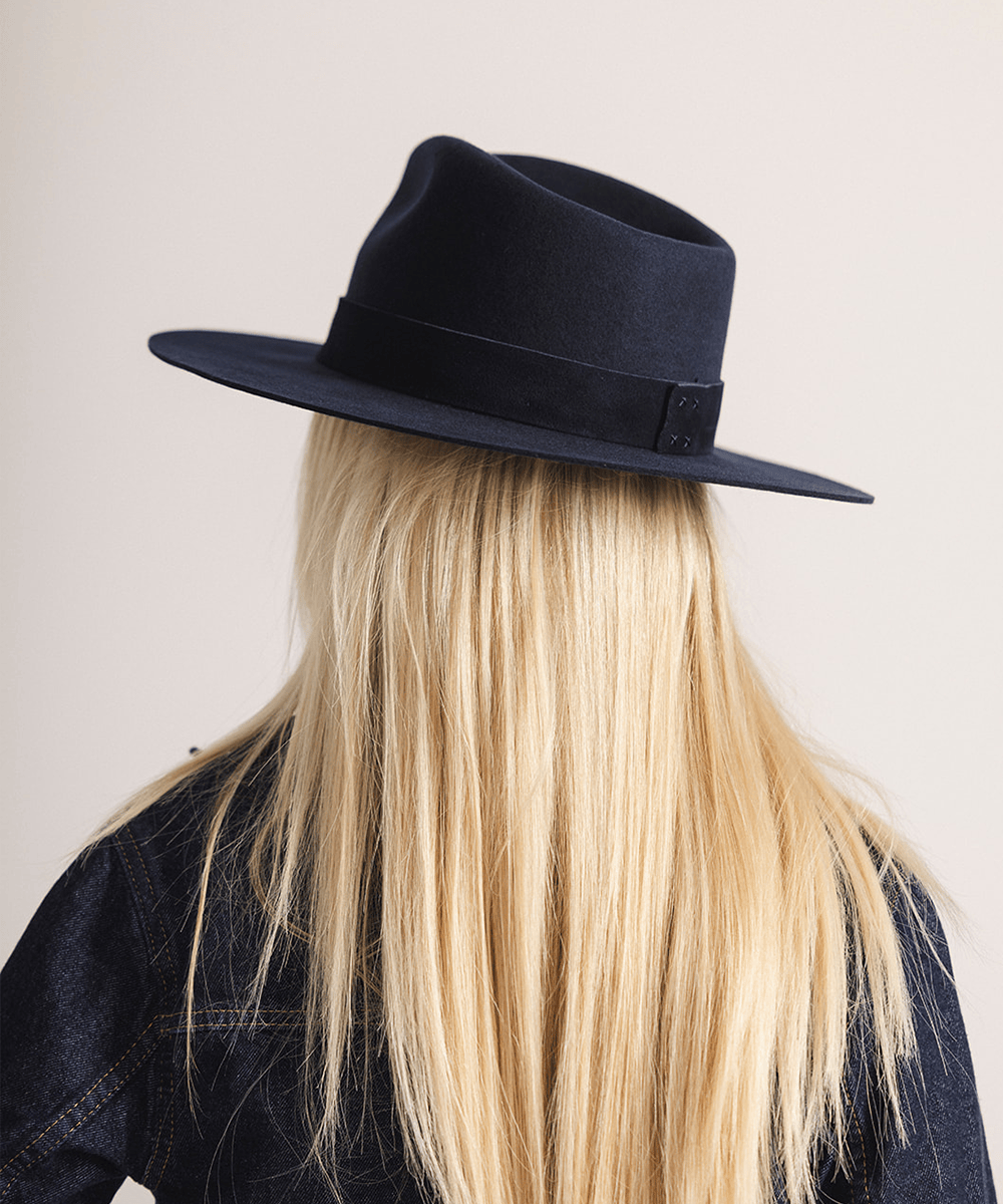 Woman wearing a navy fedora hat with a band against a white background #color_navy
