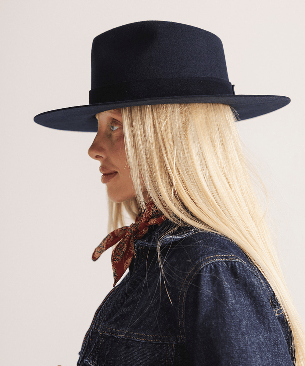 Woman wearing a navy fedora hat with a band against a white background #color_navy