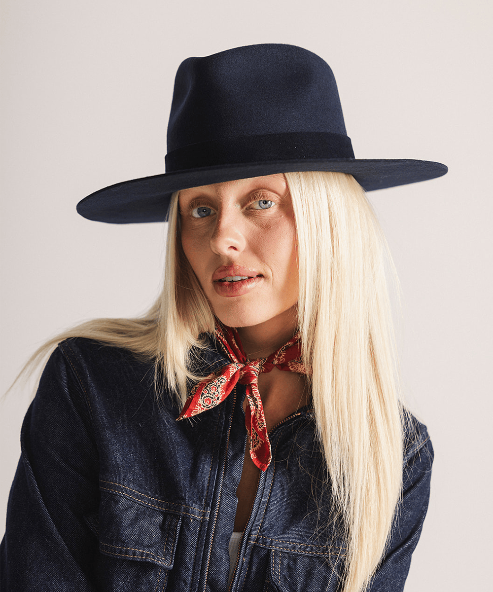 Woman wearing a navy fedora hat with a band against a white background #color_navy