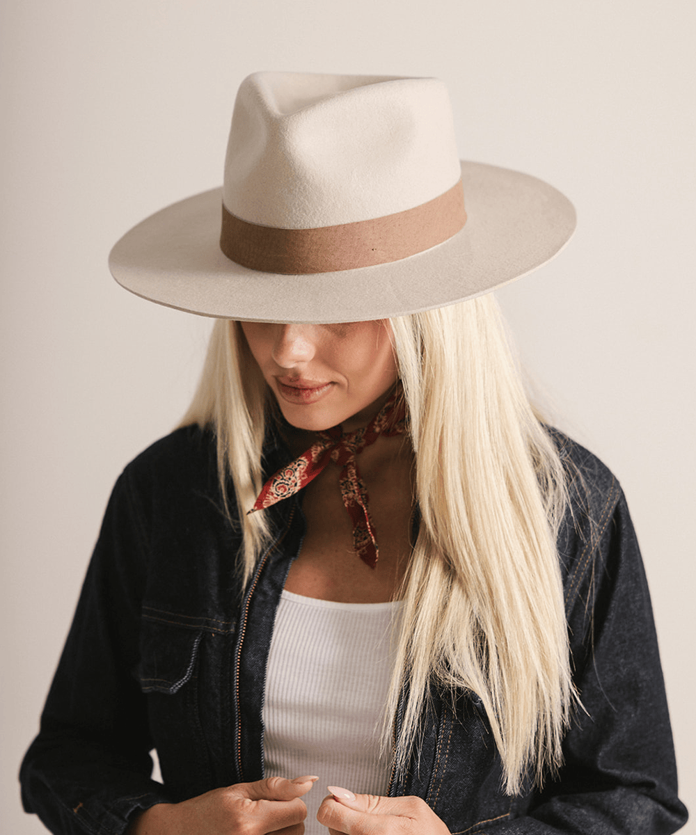Woman wearing an ivory colored fedora hat with a brown band on a white background #color_ivory