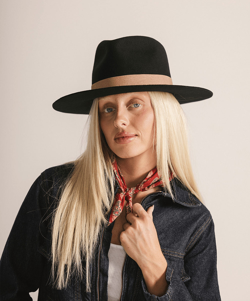 Woman wearing a black fedora hat with a brown band against a white background #color_black-brown