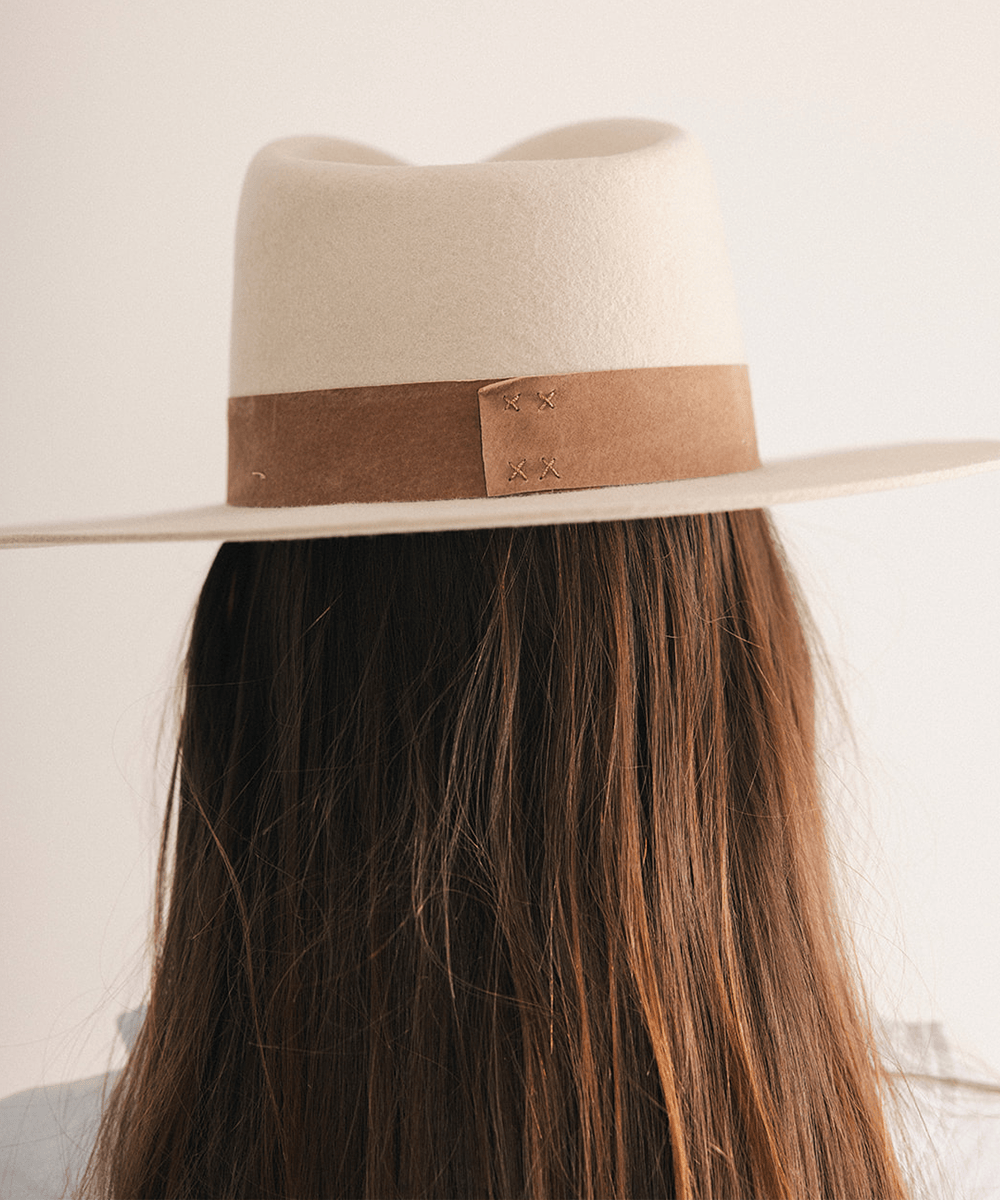 Woman wearing a fedora hat with a brown band on a white background #color_ivory