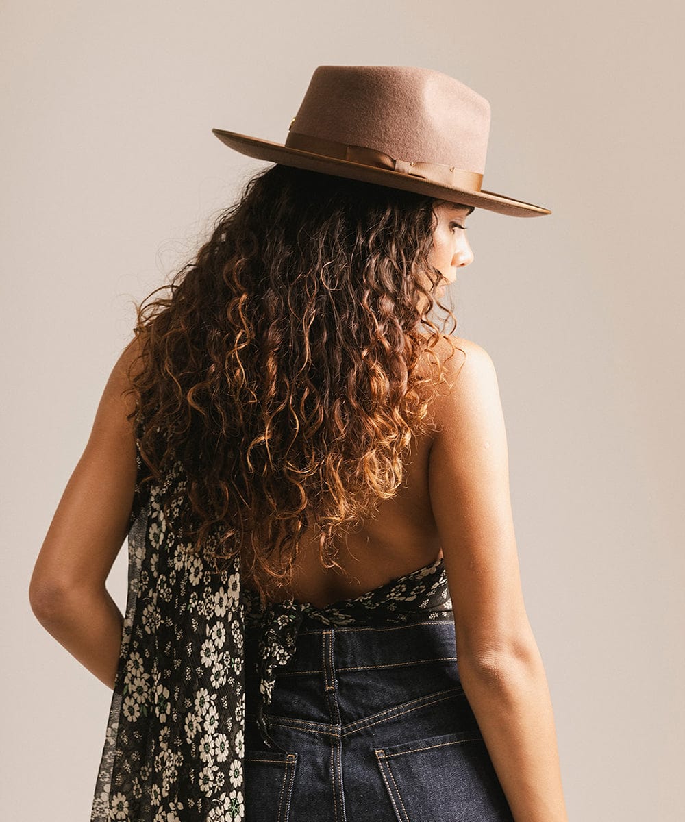 Woman wearing a brown hat, floral scarf, and denim jacket against a plain background #color_chocolate