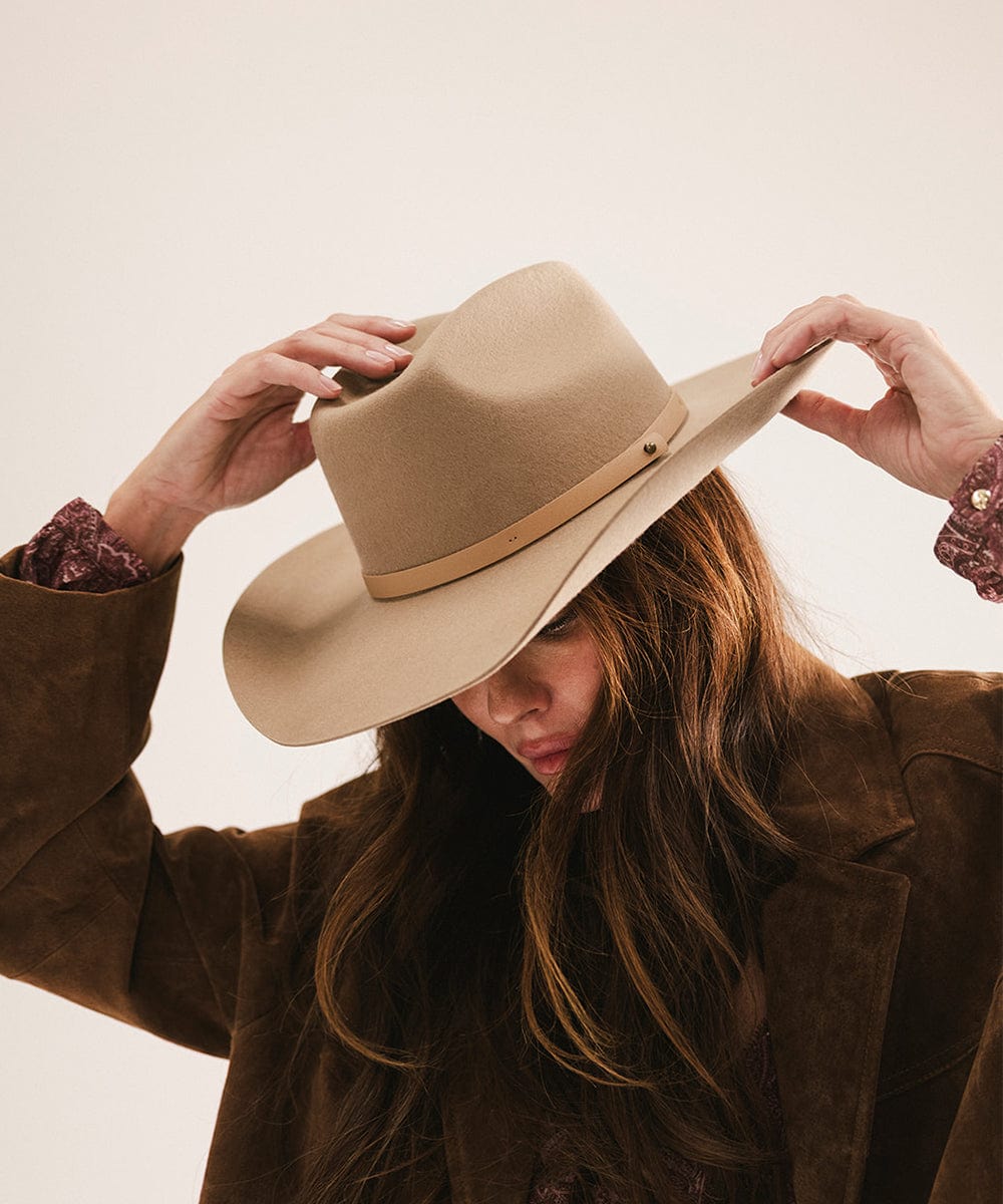 Person wearing a beige hat and brown coat against a neutral background #color_tan