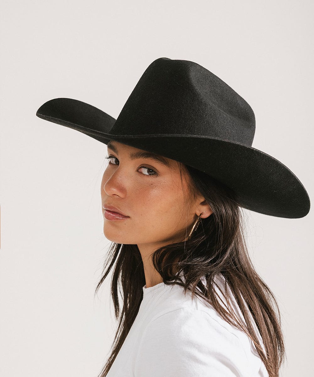 Woman wearing a black cowboy hat against a plain background #color_black