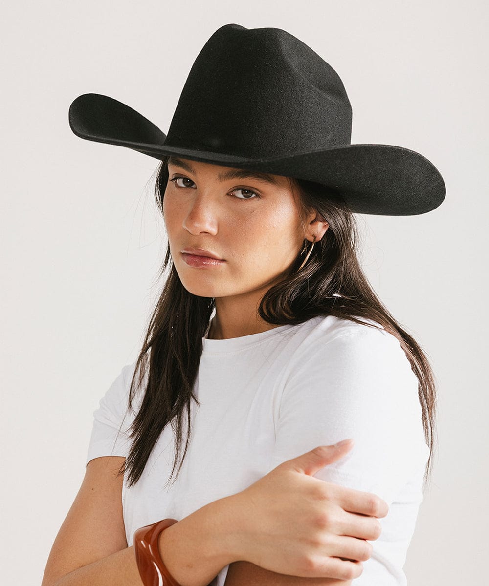 Woman wearing a black cowboy hat against a plain background #color_black