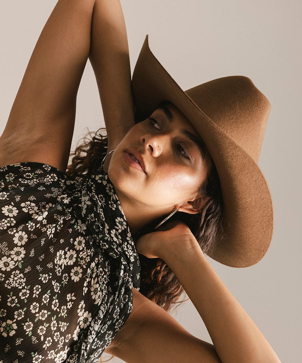 Woman wearing a wide-brimmed hat against a neutral background #color_caramel
