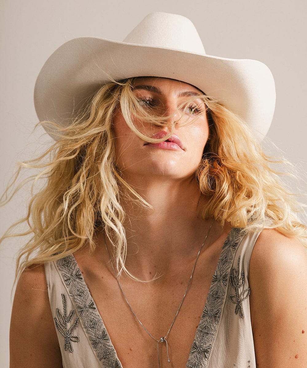 Woman wearing a white cowboy hat with a neutral background #color_off white