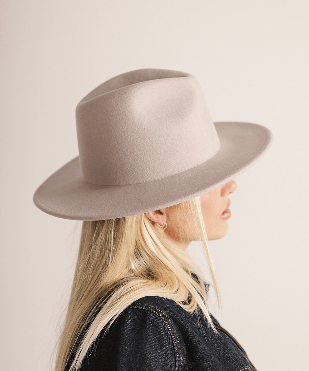 Person wearing an ivory colored fedora hat on a plain background #color_ivory