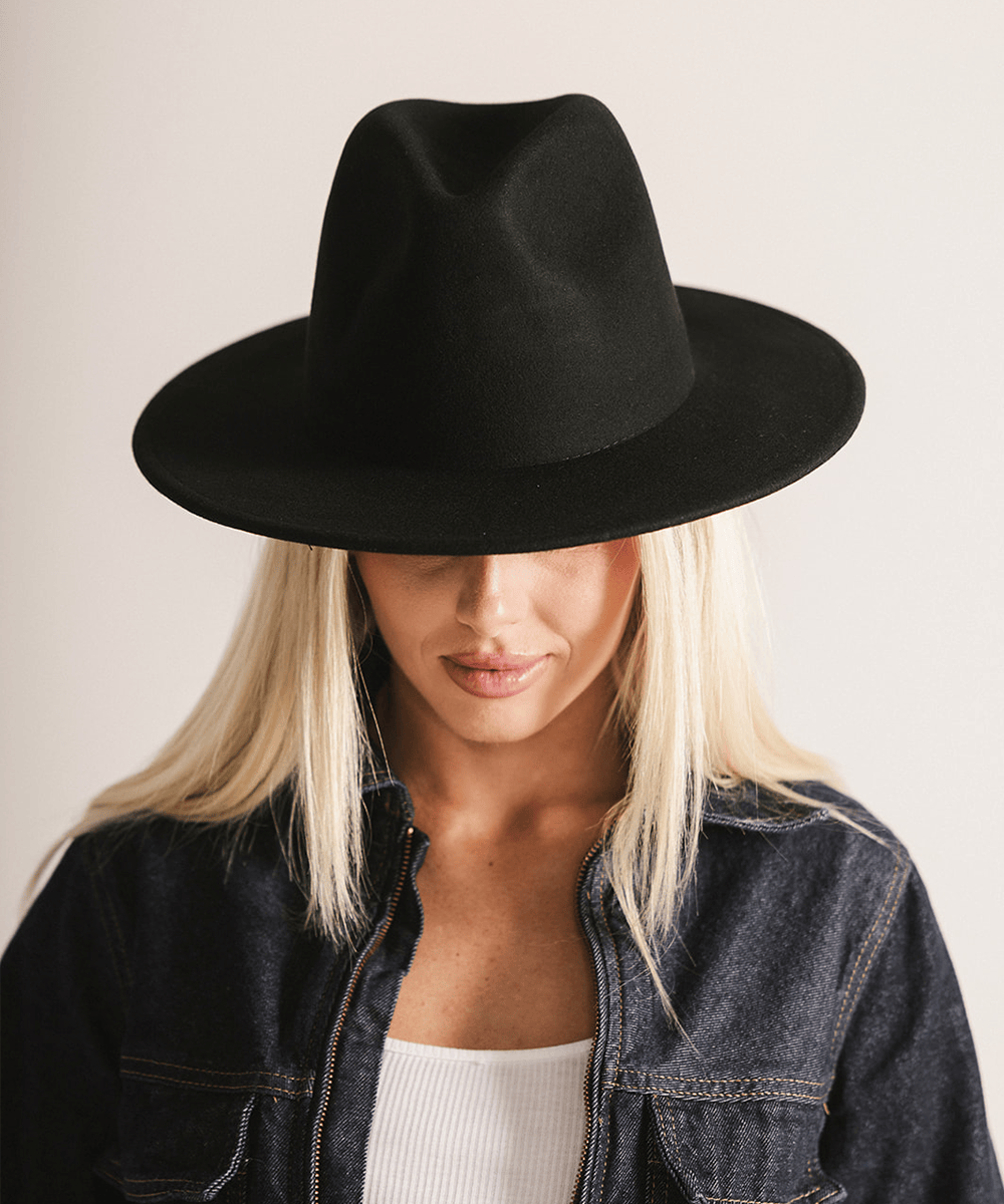 Woman wearing a black fedora hat against a plain background #color_black