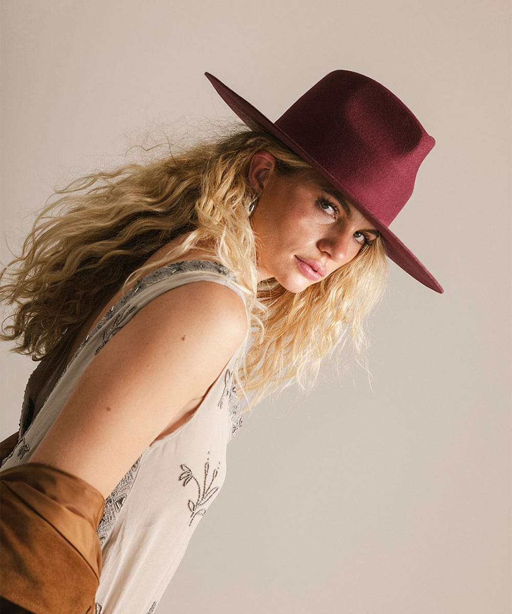 Woman wearing a maroon hat against a plain background #color_merlot