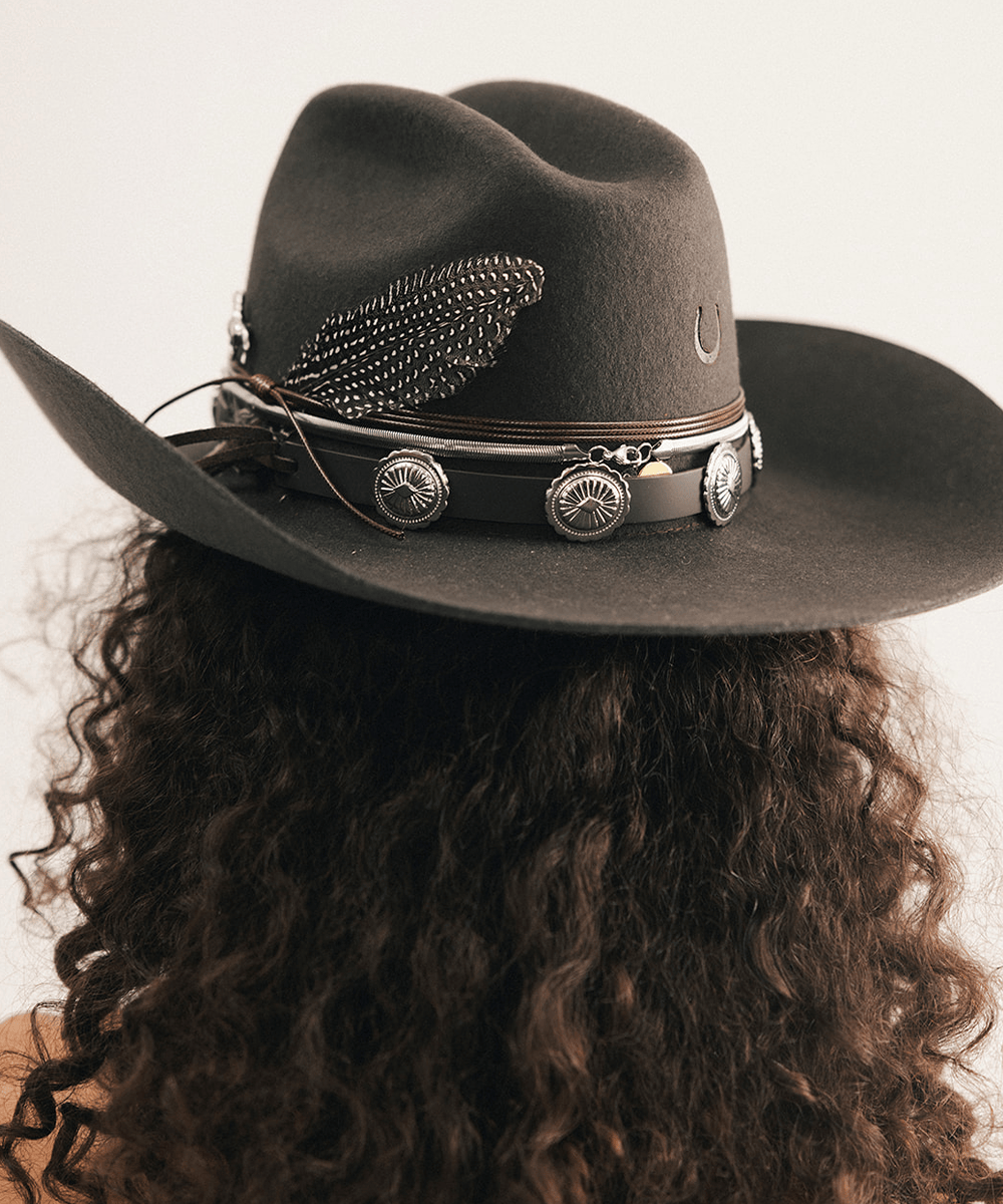Woman wearing a cowboy hat and strapless denim dress against a plain background #color_dark brown
