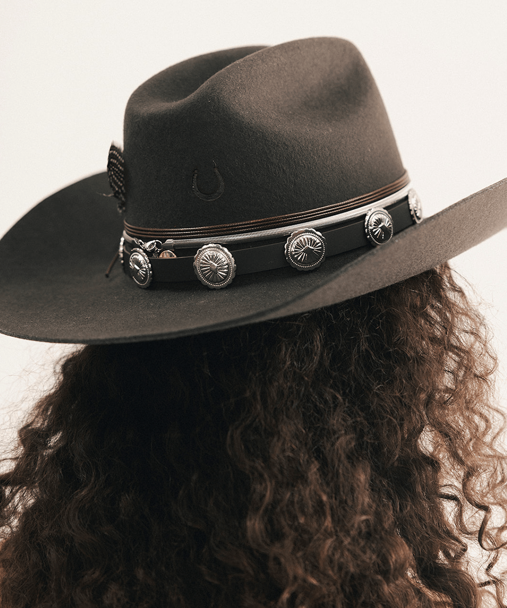 Woman wearing a cowboy hat and strapless denim dress against a plain background #color_dark brown