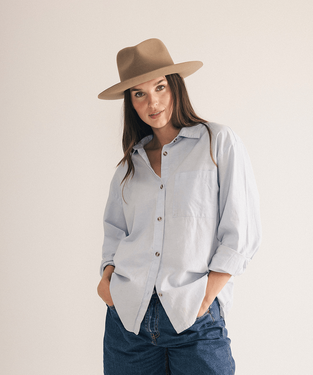 Woman wearing a brown fedora hat with a neutral background #color_brown