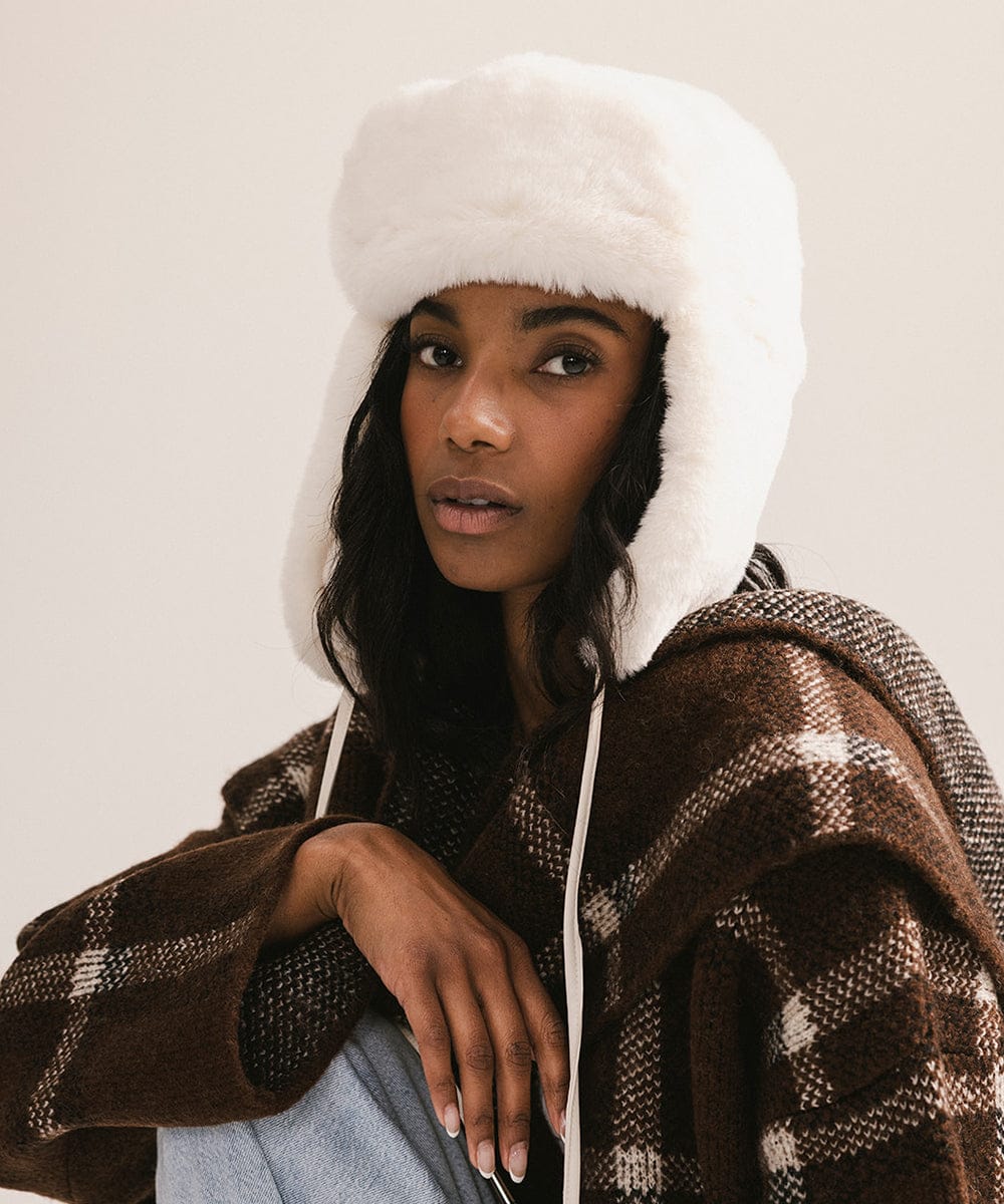 Person wearing a white hooded coat with a patterned brown garment underneath on a plain background #color_winter white