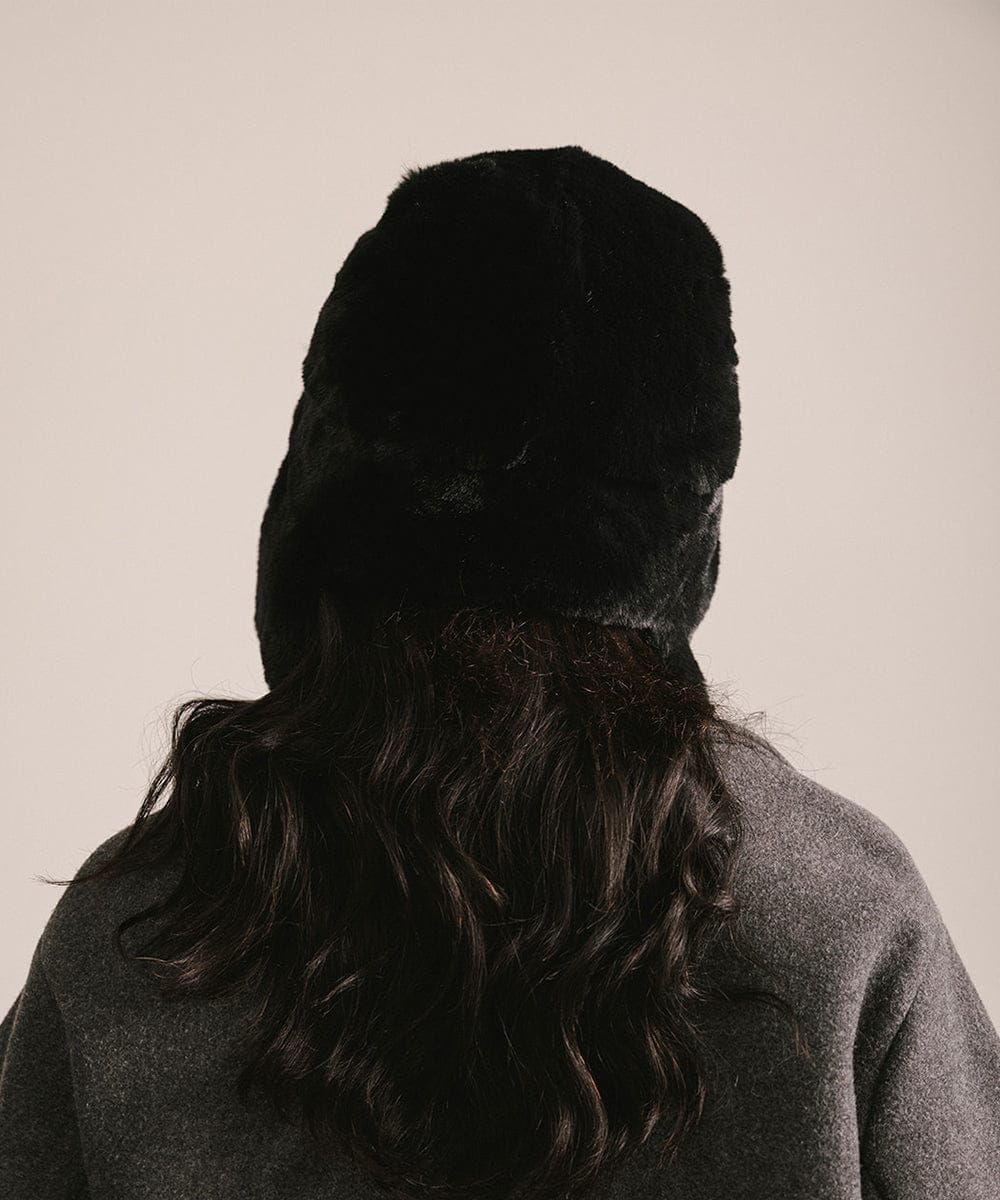 Person wearing a black fur hat from behind on a beige background #color_black