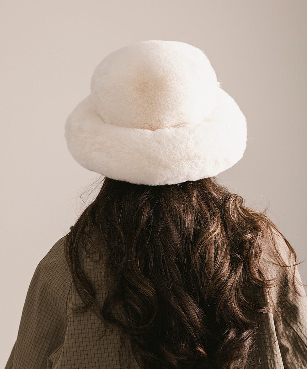 Person wearing a white fur hat with a plain background #color_winter white