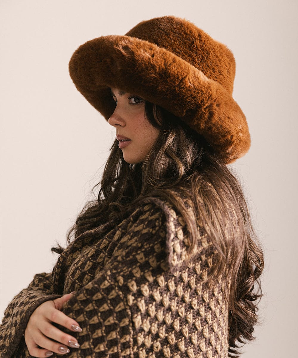 Woman wearing a brown fur hat and patterned coat against a neutral background #color_brown