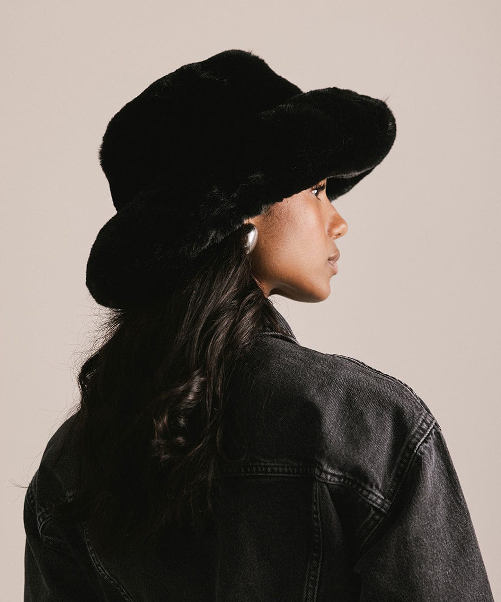 Person wearing a black hat and black jacket against a beige background #color_black