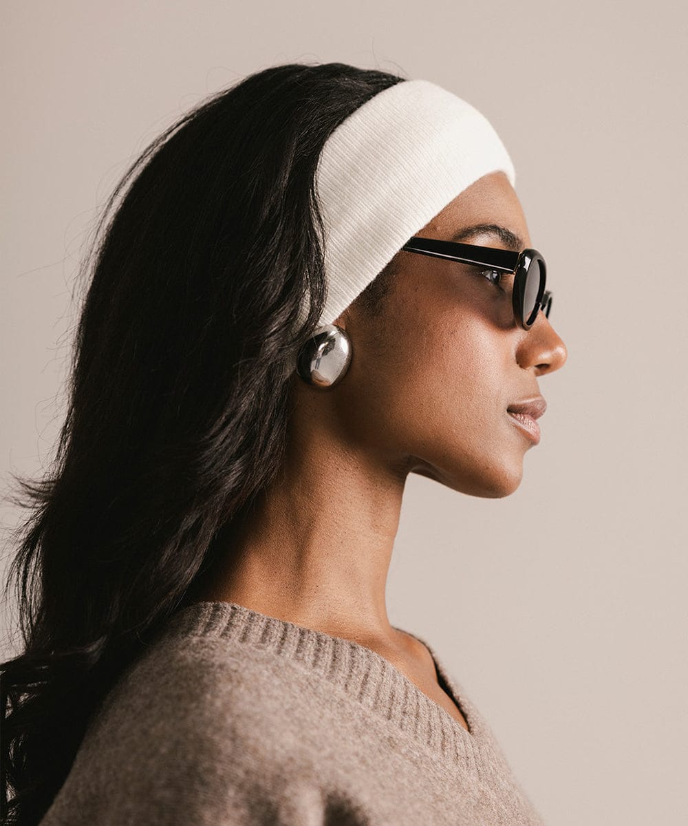 Woman wearing a white headband and glasses with a neutral background #color_ivory