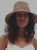 Woman wearing a woven bucket hat against a plain background #color_natural brown
