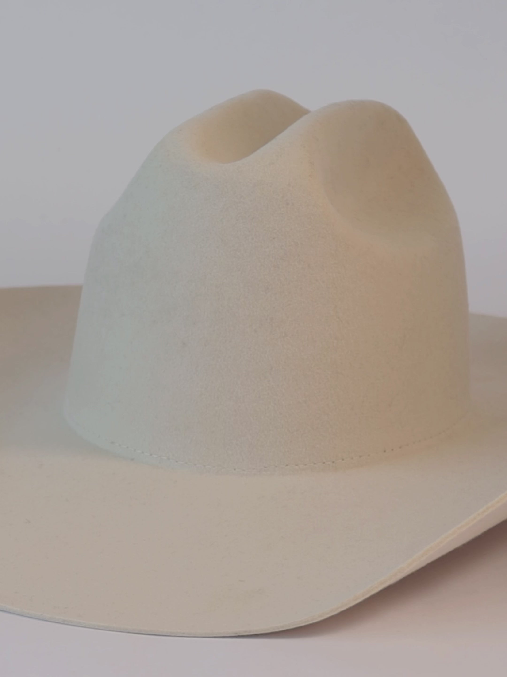A video of a white cowboy hat being decorated with bands, lightning brand, and a star pin #color_off white