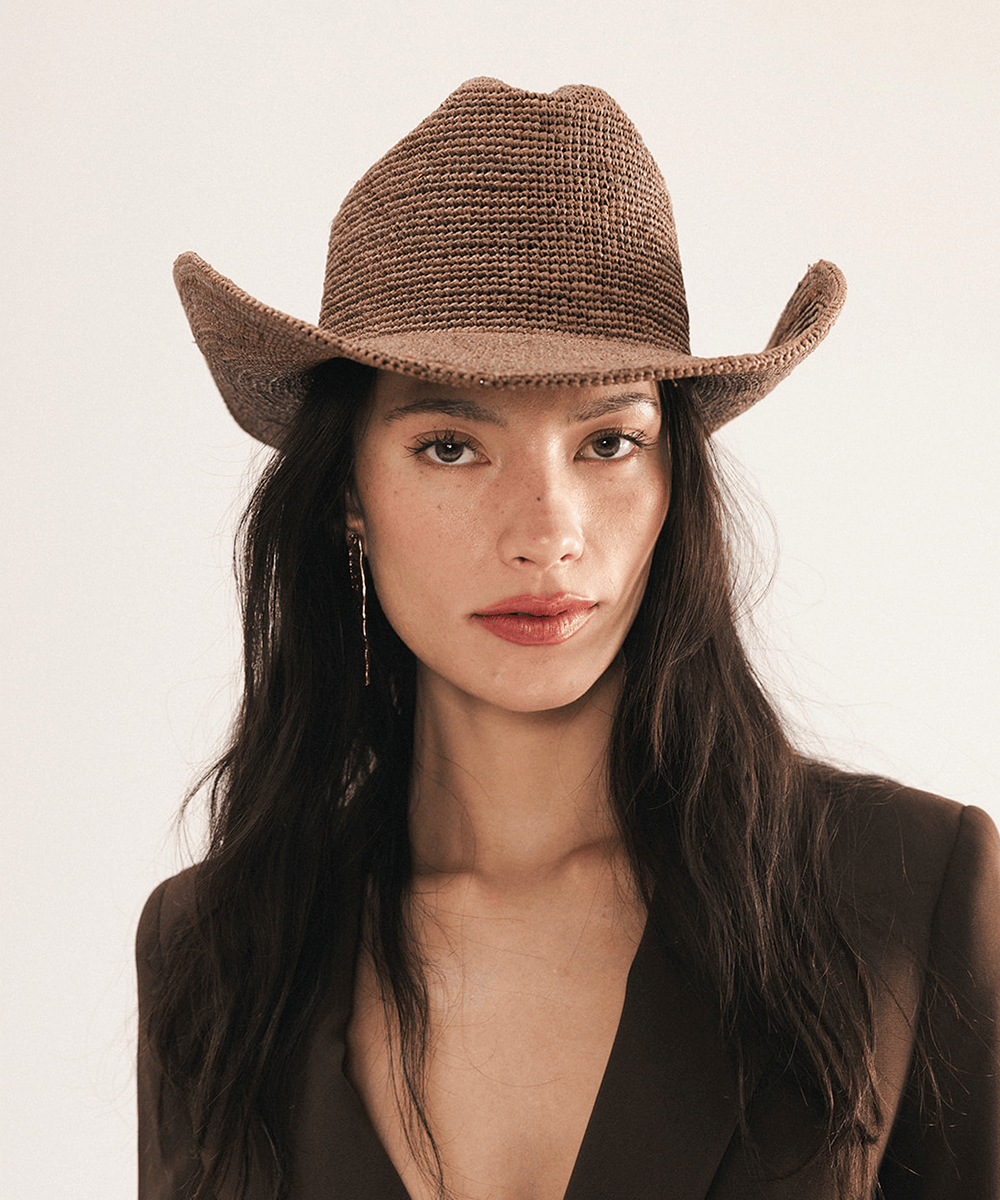 Woman wearing a chocolate colored straw cowboy hat on a white background #color_chocolate