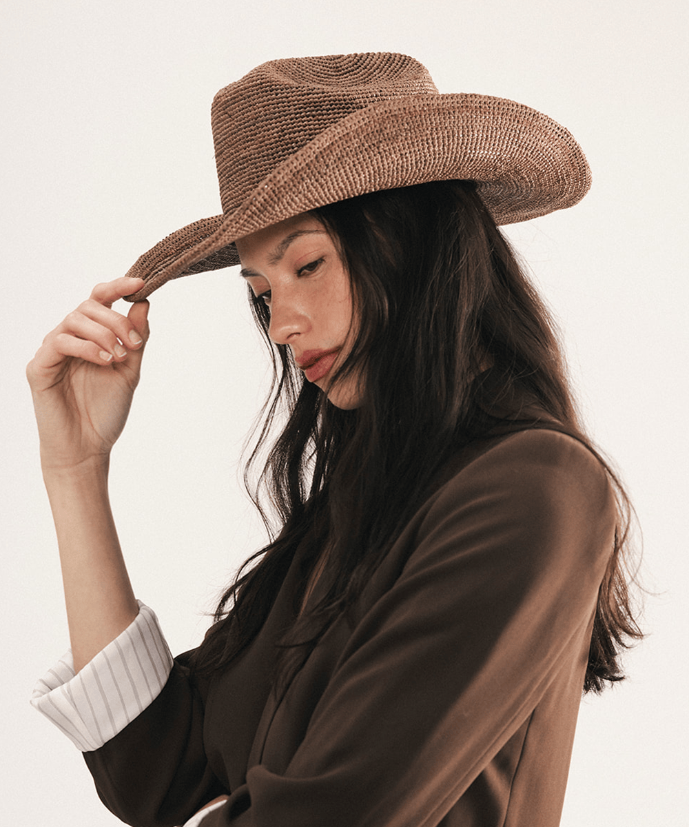 Woman wearing a chocolate colored straw cowboy hat on a white background #color_chocolate