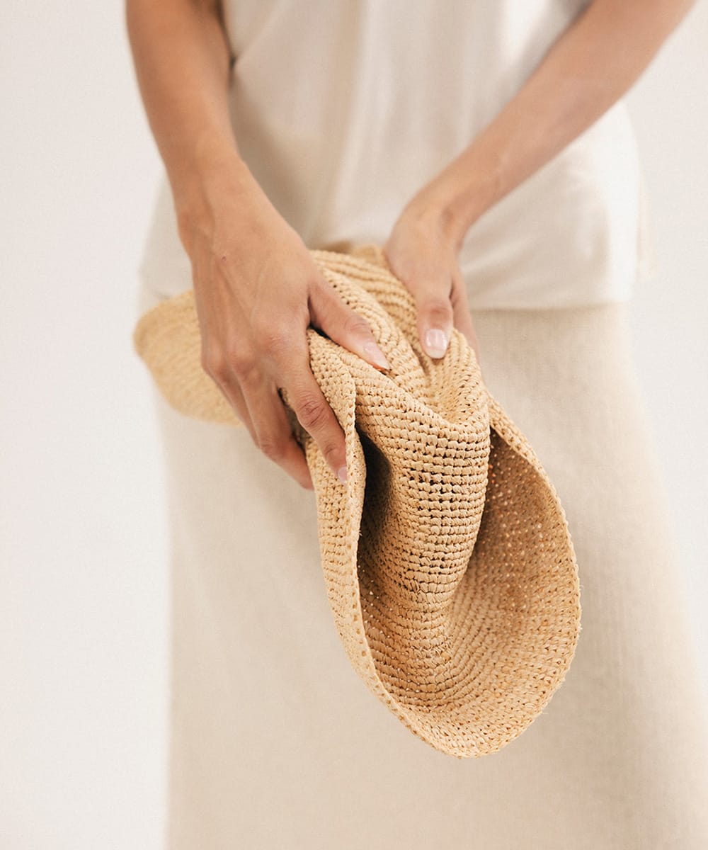 Person holding a straw hat against a plain background #color_natural