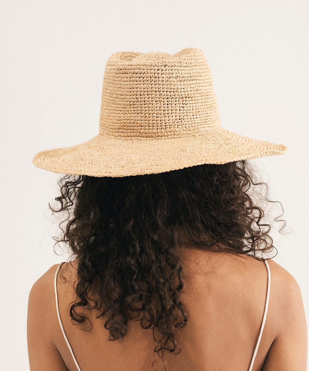 Woman wearing a straw hat against a plain background #color_natural
