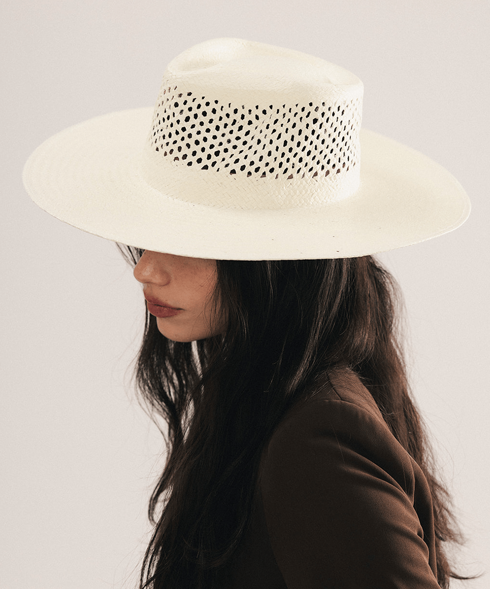 Woman wearing a natural white straw fedora hat with a wide brim and intricate venting details. #color_natural white