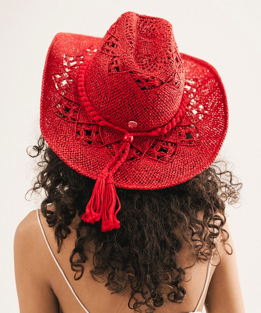 Woman wearing a red crochet cowboy hat against a plain background #color_cherry red