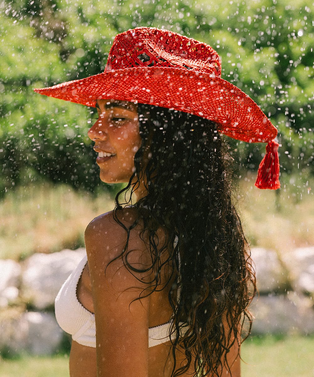 Woman wearing a red crochet cowboy hat against outdoors #color_cherry red