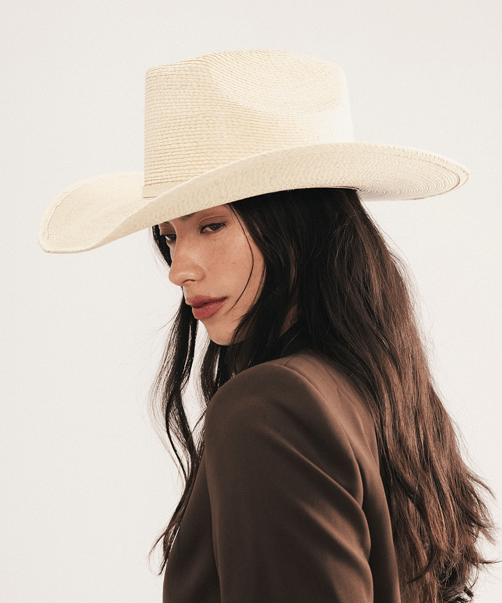 Woman wearing a natural colored straw cowgirl hat and brown blazer on a light background #color_natural