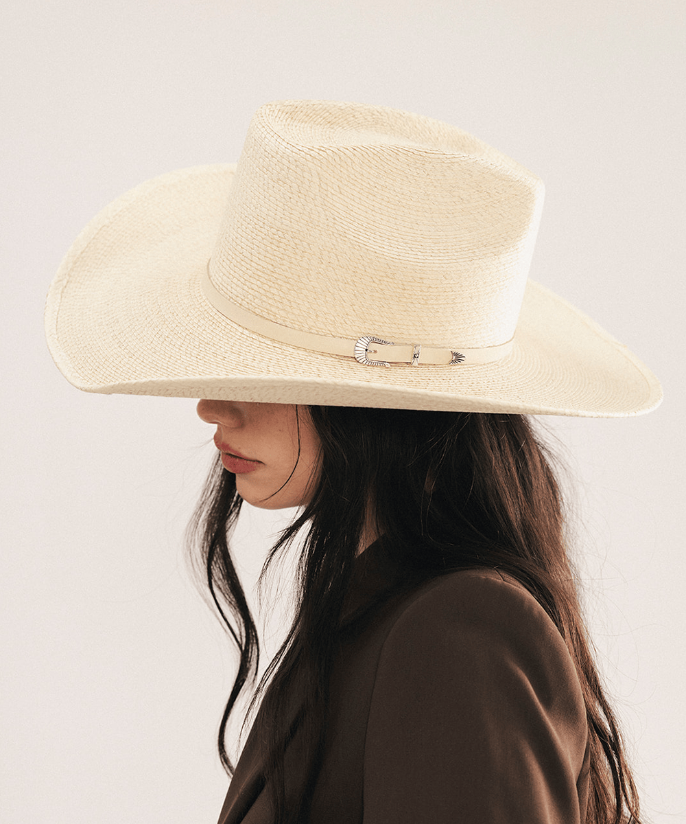 Woman wearing a natural colored straw cowgirl hat and brown blazer on a light background #color_natural