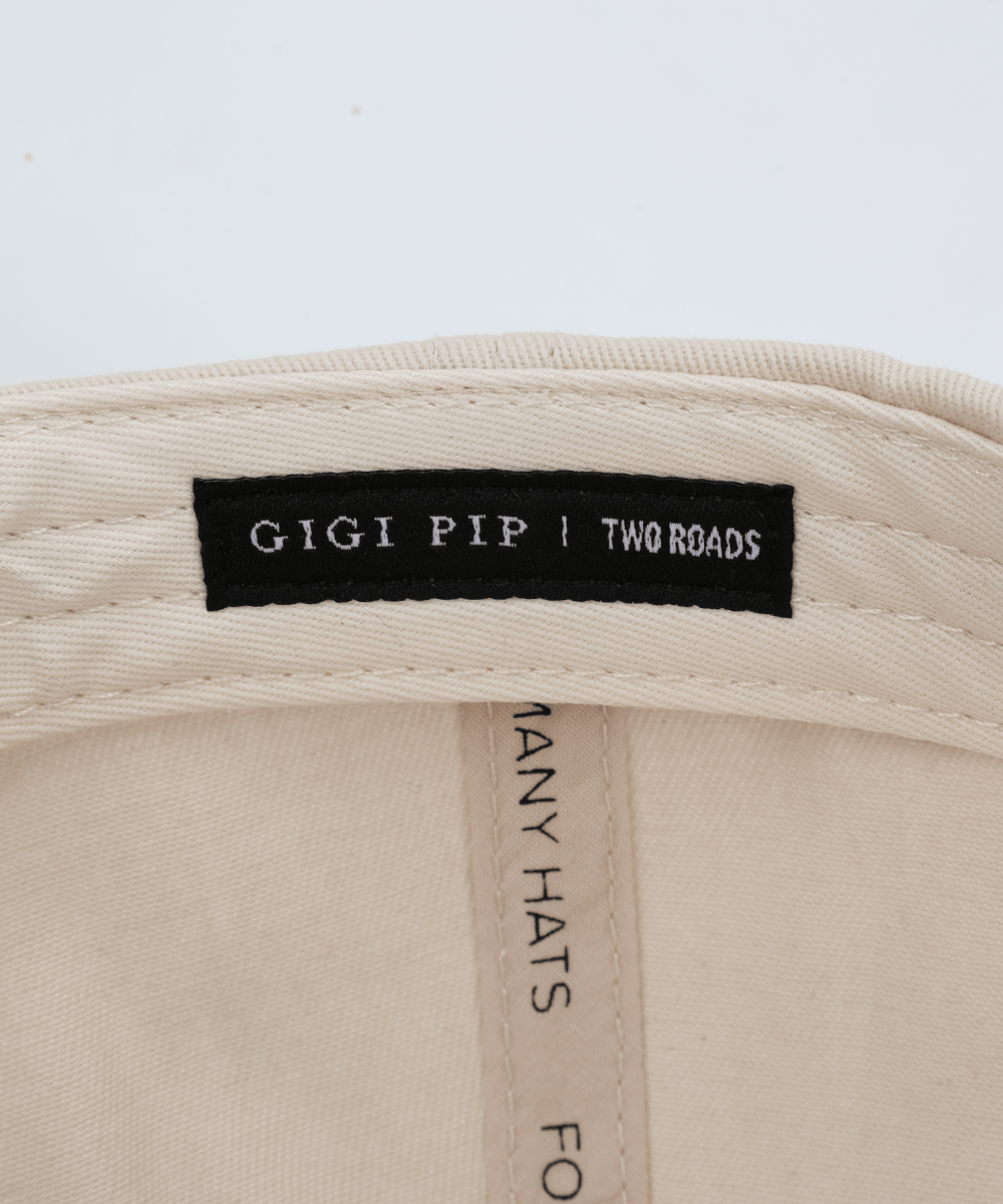 Embroidery inside a hat that says 'GIGI PIP | TWO ROADS' in a white background #color_cream - black