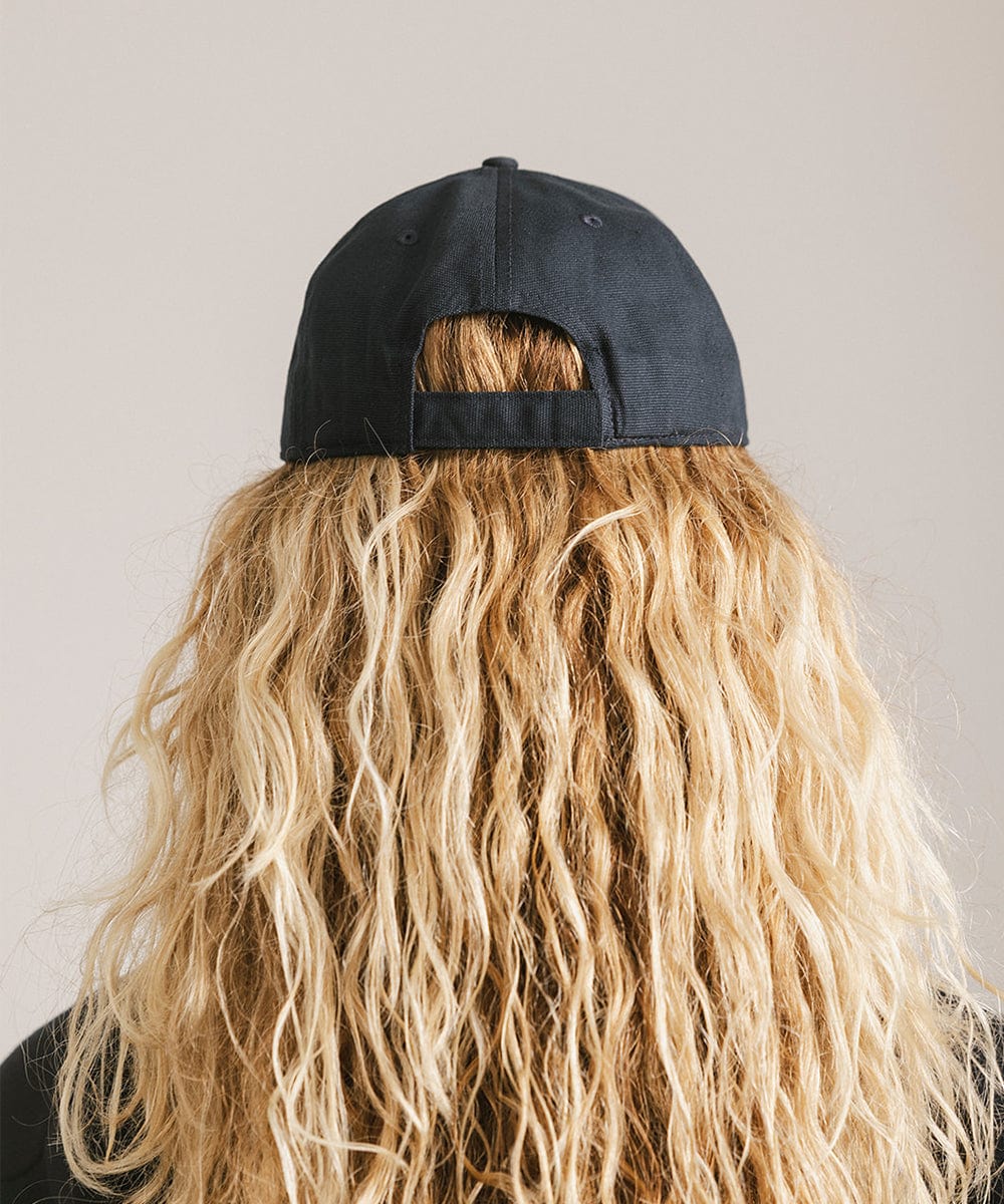 Woman with long hair wearing a navy cap against a plain background  #color_navy