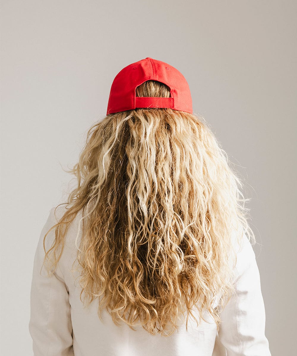 Woman with long hair wearing a red cap and a white coat against a plain background #color_red