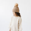 Gigi Pip beanies for kids - Milo Beanie - soft knit ribbers kid's beanie featuring a fold up brim with a rose gold Gigi Pip logo pin on the side of the fold and a pom pom on the center of the crown [camel]
