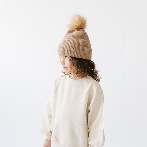 Gigi Pip beanies for kids - Milo Beanie - soft knit ribbers kid's beanie featuring a fold up brim with a rose gold Gigi Pip logo pin on the side of the fold and a pom pom on the center of the crown [camel]