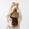 Gigi Pip beanies for kids - Milo Beanie - soft knit ribbers kid's beanie featuring a fold up brim with a rose gold Gigi Pip logo pin on the side of the fold and a pom pom on the center of the crown [camel]