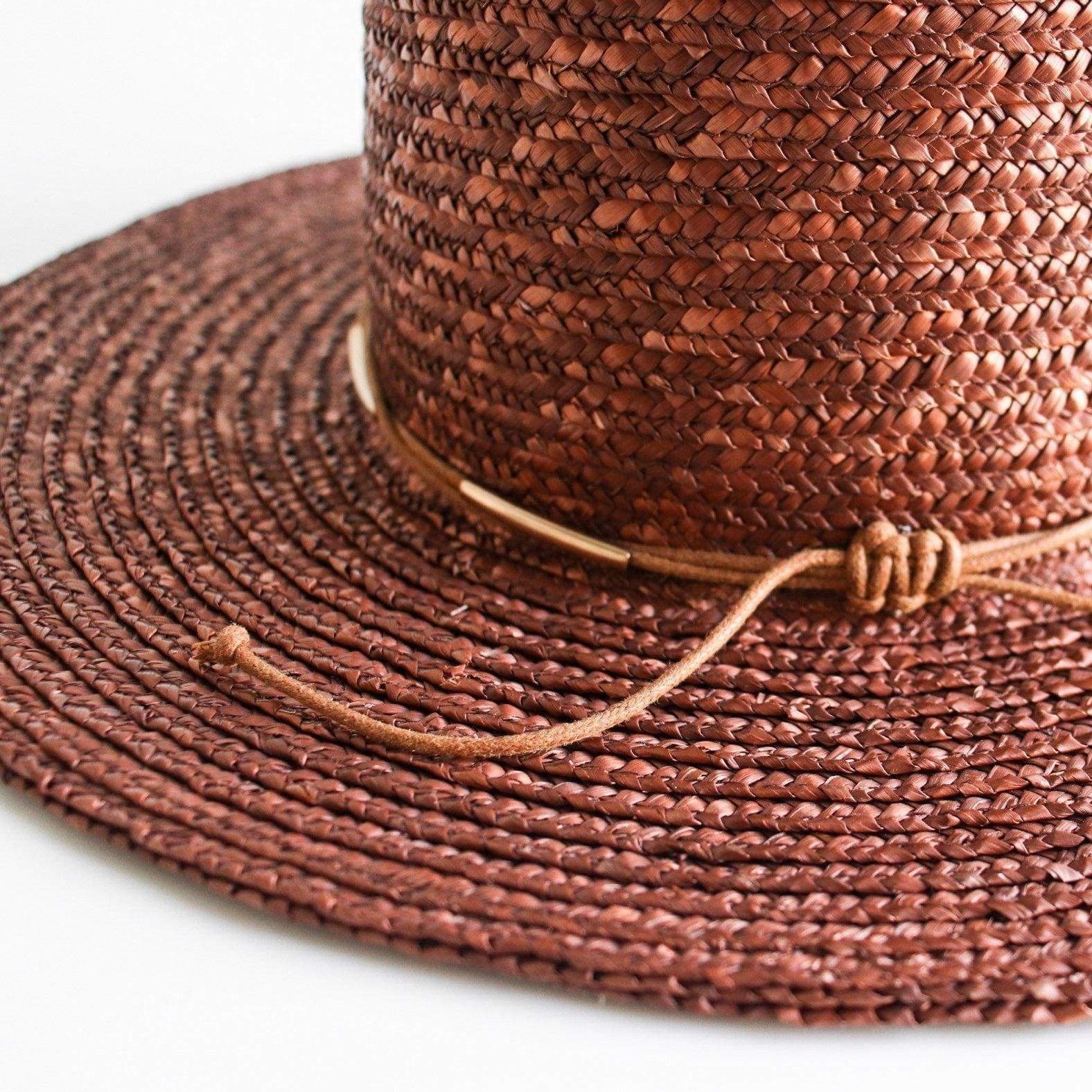 Close up image of a brown boater-style straw hat with a flat brim and a hat band on a white background #color_brown